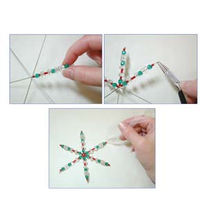 Hands threading beads onto the large wire snowflake form to create a colourful ornament